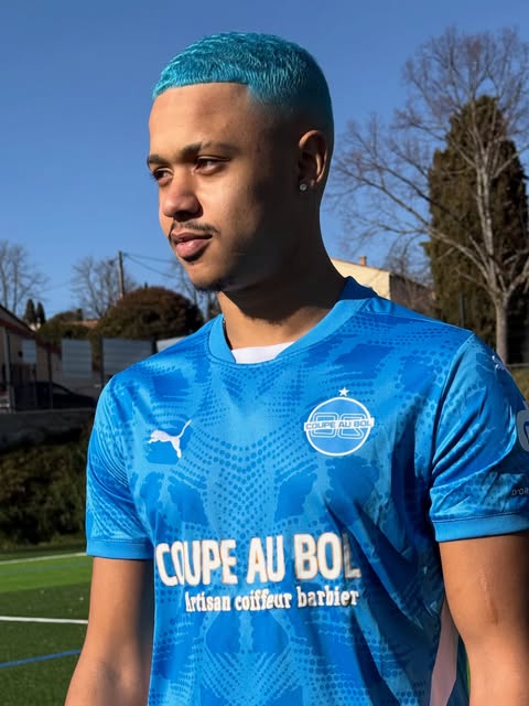 Client aux cheveux teints bleu glacier portant le maillot Coupe au Bol sur un terrain de foot