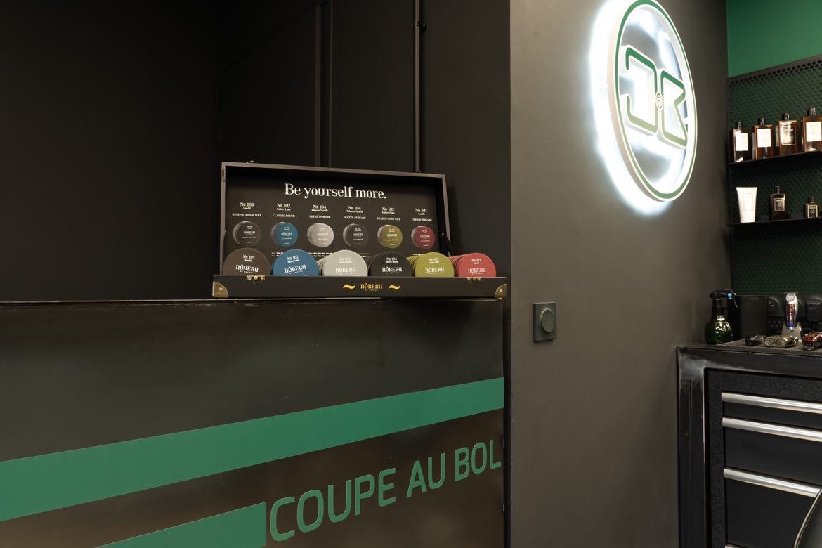 Coffret de pommades Nōberu of Sweden posé sur le comptoir du salon, logo lumineux Coupe au Bol en arrière-plan