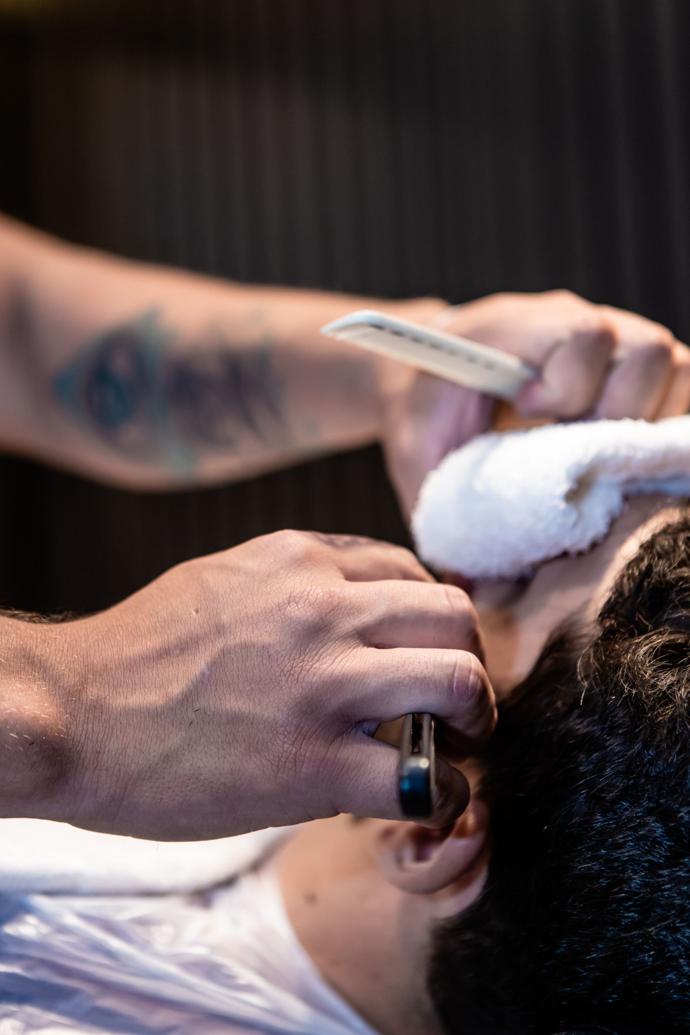 Un barbier applique une serviette chaude sur le visage d’un client